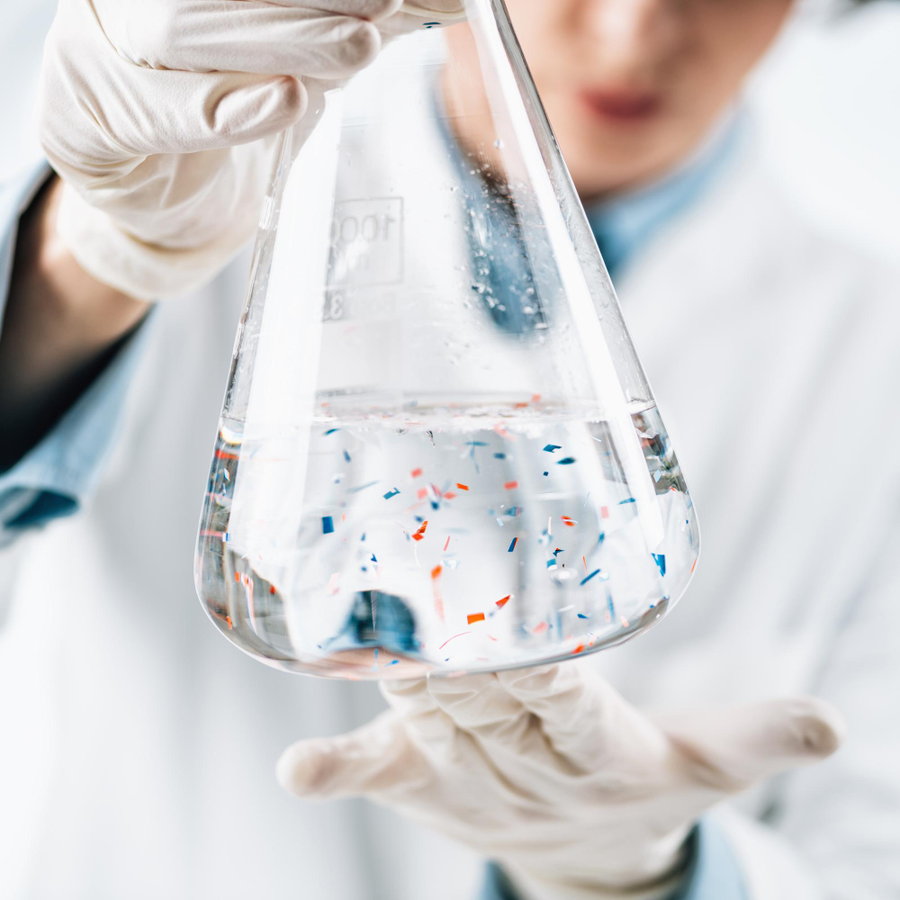 Laboratory technician holding a flask of water containing visible particles